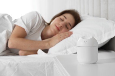 Photo of Woman sleeping at home, focus on essential oil aroma diffuser