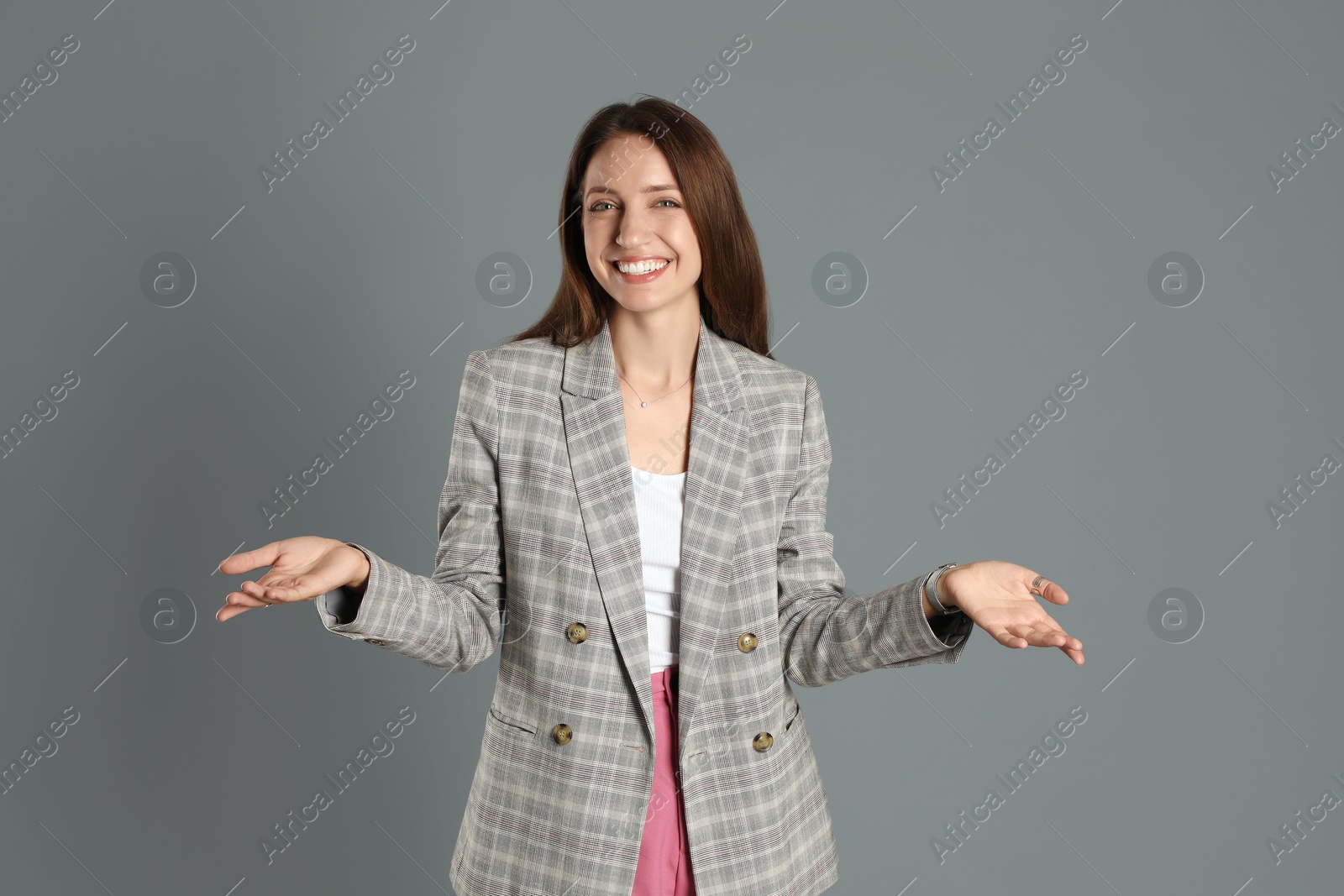 Photo of Beautiful woman in stylish jacket and pink pants on grey background