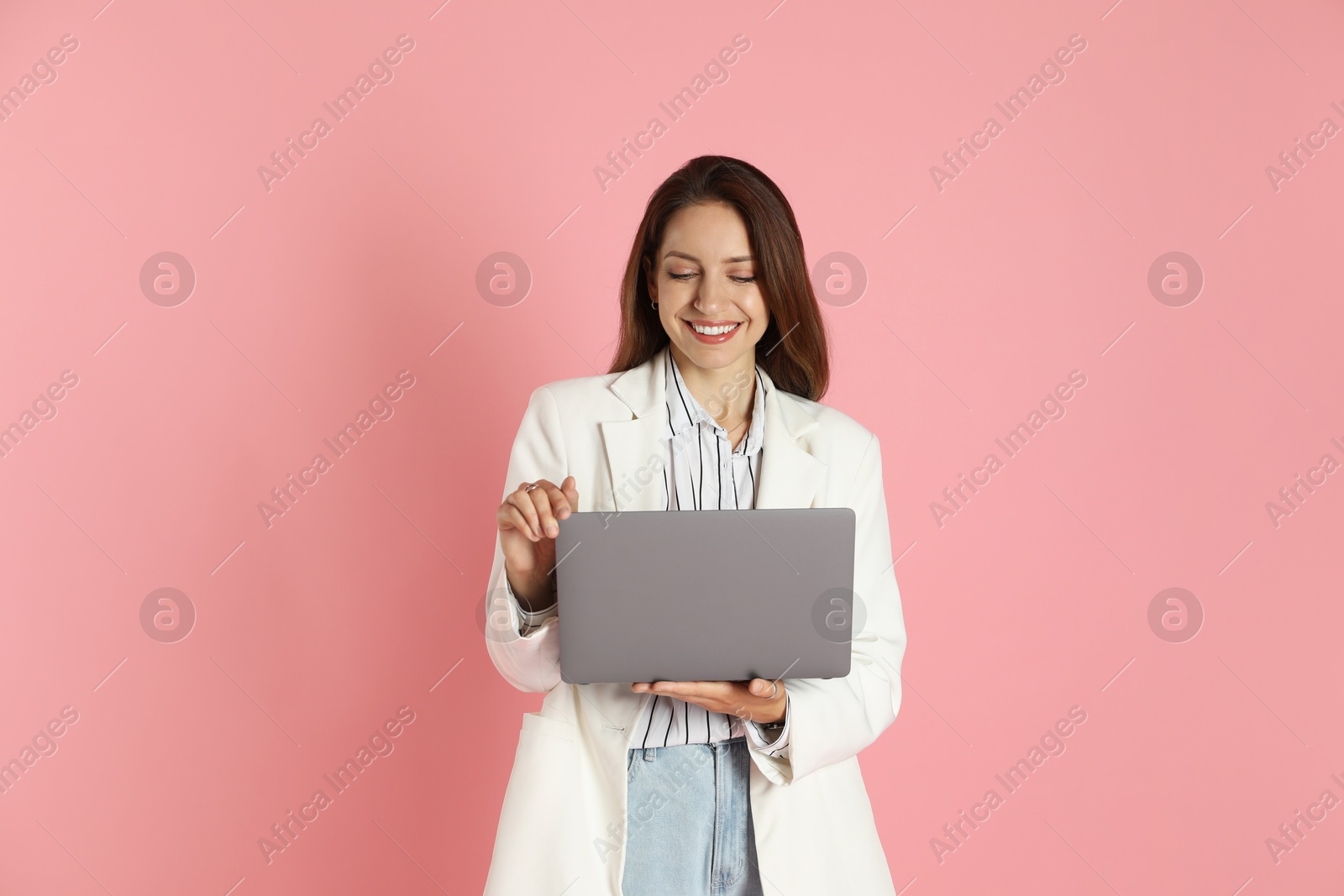 Photo of Beautiful woman in stylish white jacket with laptop on pink background