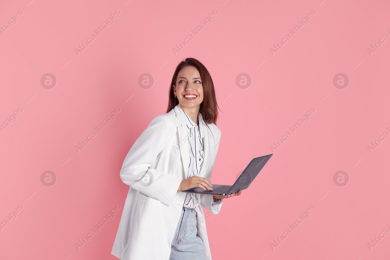 Photo of Beautiful woman in stylish white jacket with laptop on pink background