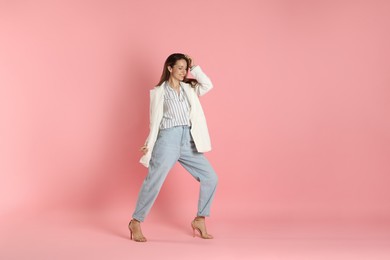 Beautiful woman in stylish white jacket on pink background