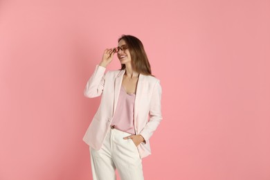 Photo of Beautiful woman in stylish white suit and sunglasses on pink background