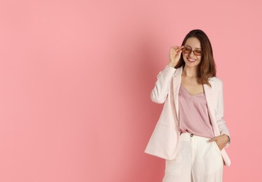 Photo of Beautiful woman in stylish white suit and sunglasses on pink background, space for text