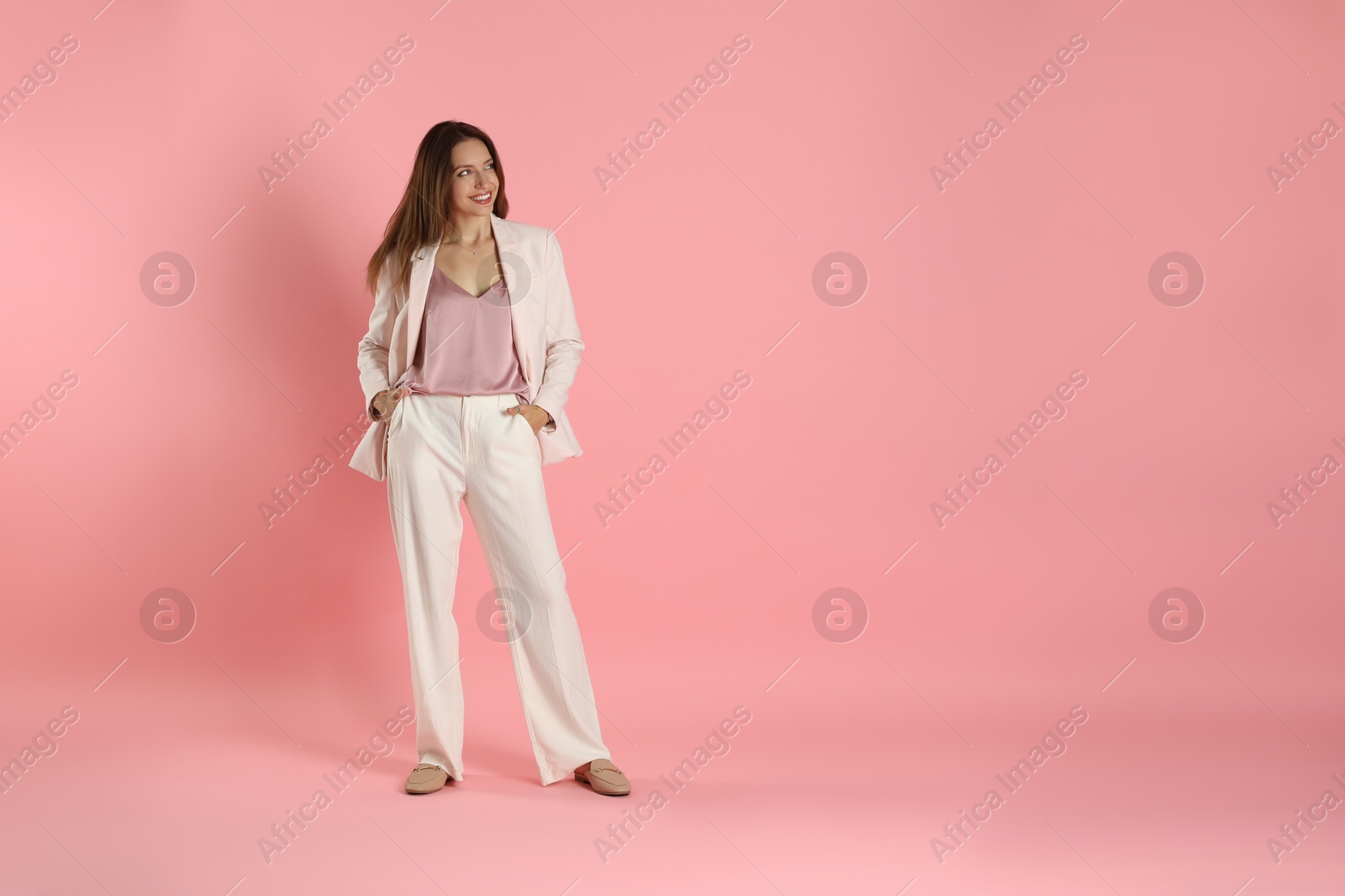 Photo of Beautiful woman in stylish white suit on pink background, space for text