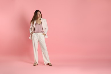 Beautiful woman in stylish white suit on pink background, space for text