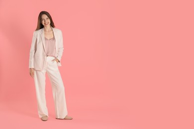 Beautiful woman in stylish white suit on pink background, space for text