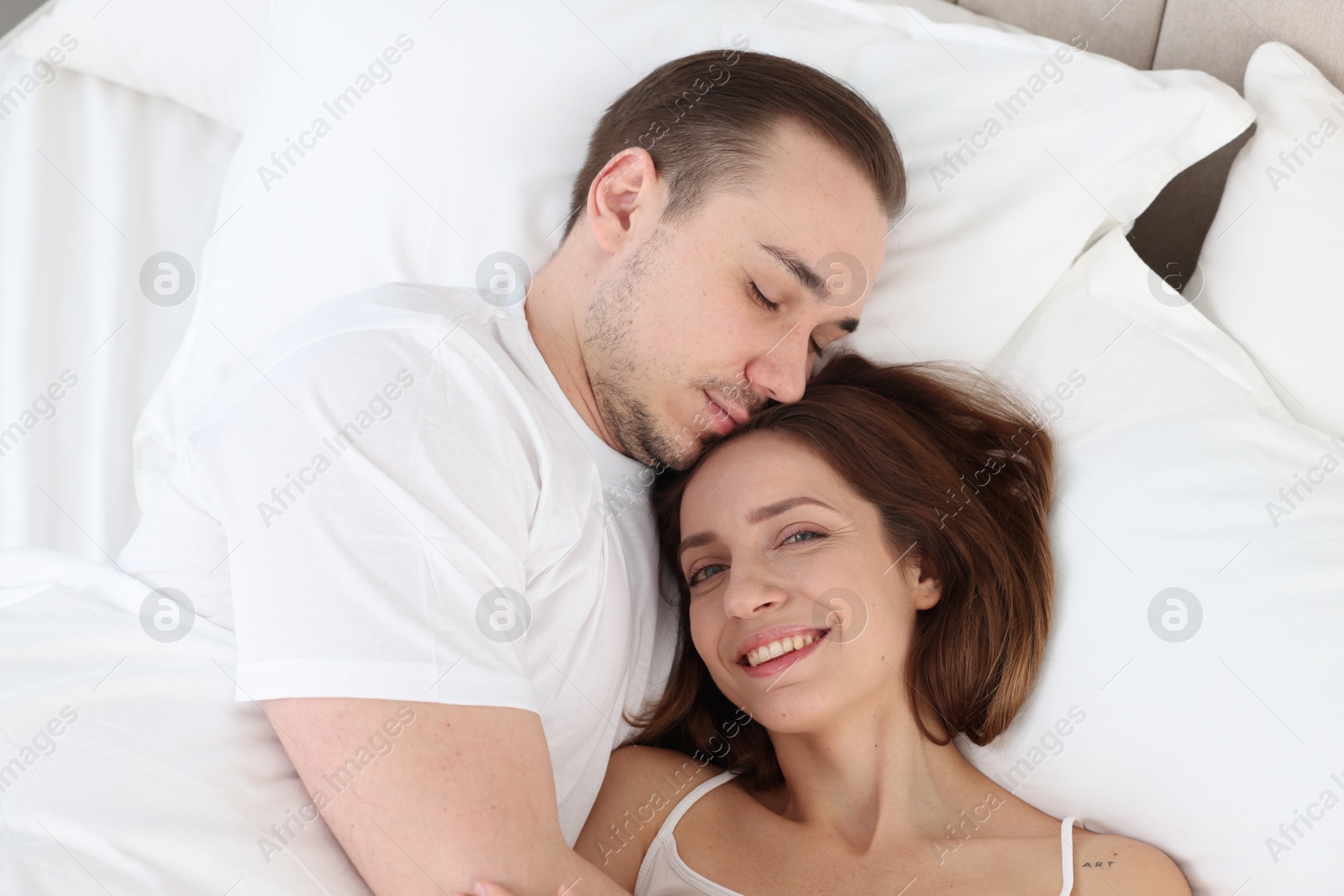 Photo of Cute couple lying in bed at home, top view