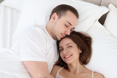 Photo of Cute couple lying in bed at home, top view