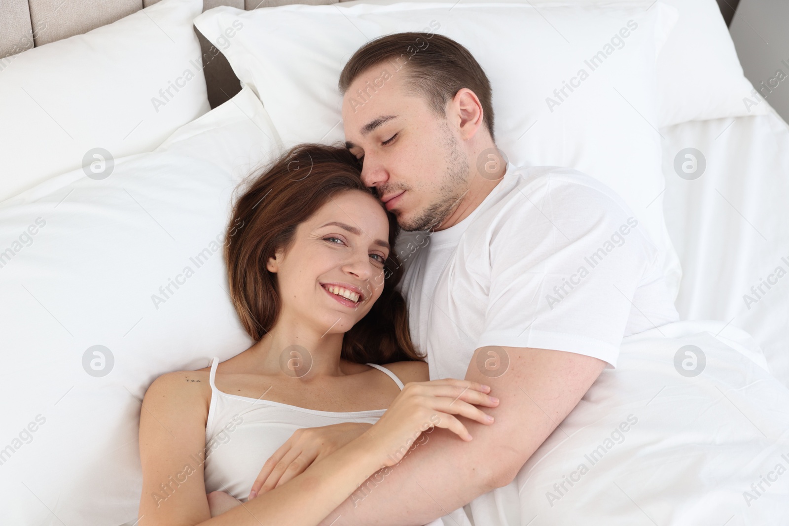 Photo of Cute couple lying in bed at home, top view