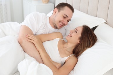 Happy couple lying in bed at home