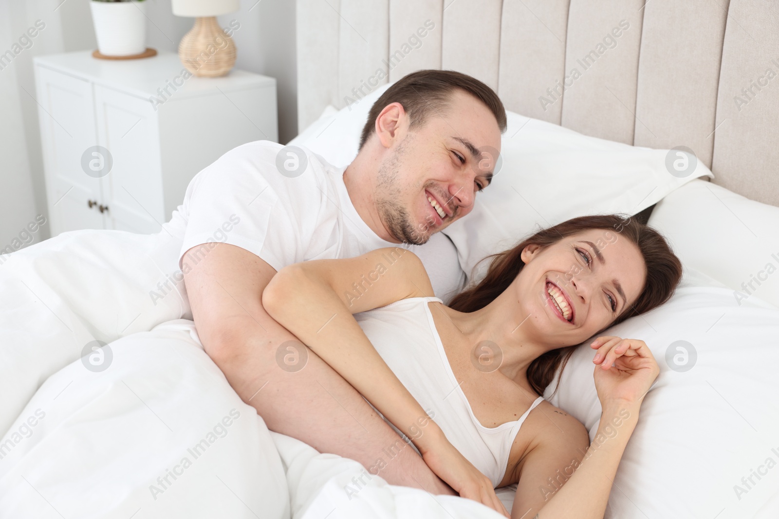 Photo of Happy couple lying in bed at home