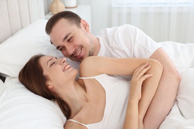 Happy couple lying in bed at home