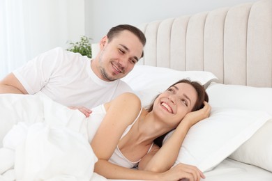 Photo of Happy couple lying in bed at home