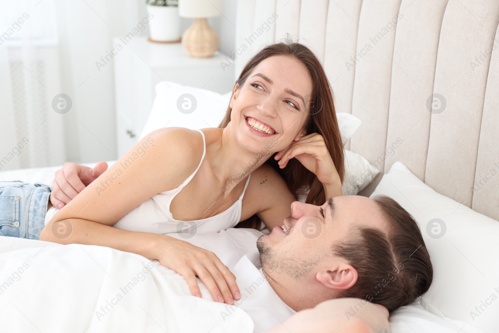 Photo of Happy couple spending time together on bed at home