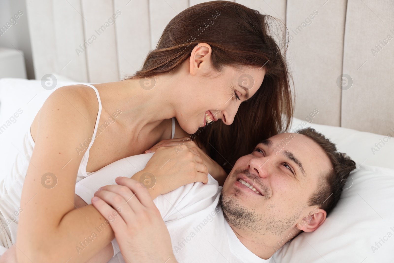 Photo of Happy couple lying on bed at home