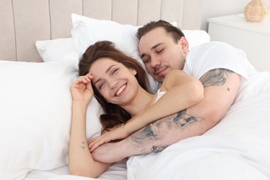 Happy couple hugging in bed at home