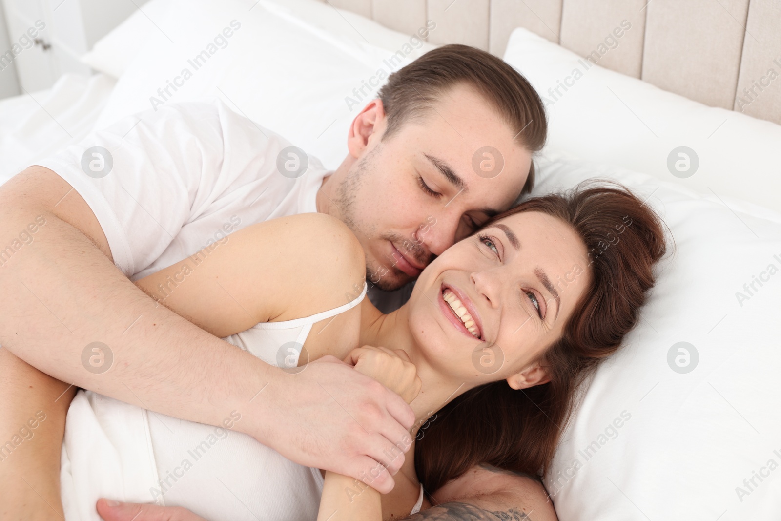 Photo of Happy couple hugging in bed at home