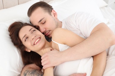 Happy couple hugging in bed at home