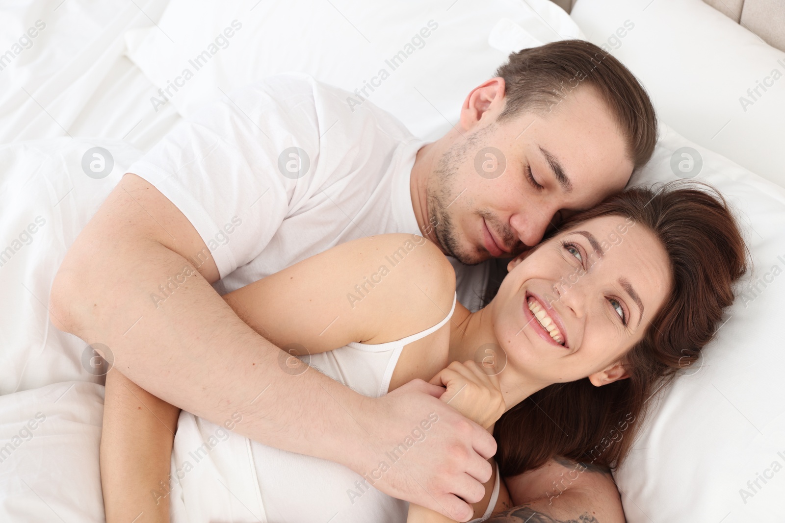 Photo of Happy couple hugging in bed at home