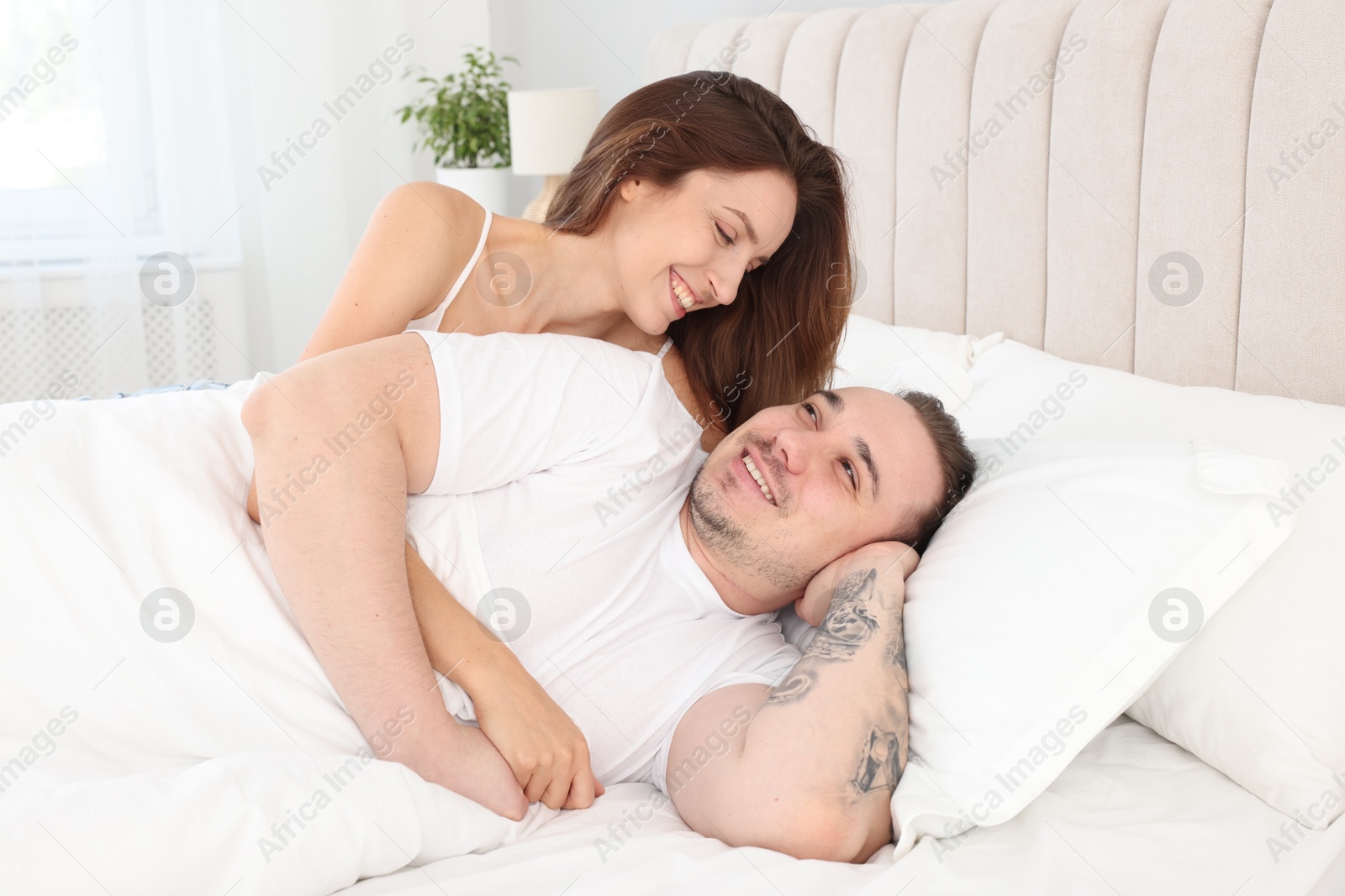 Photo of Happy couple spending time together in bed at home