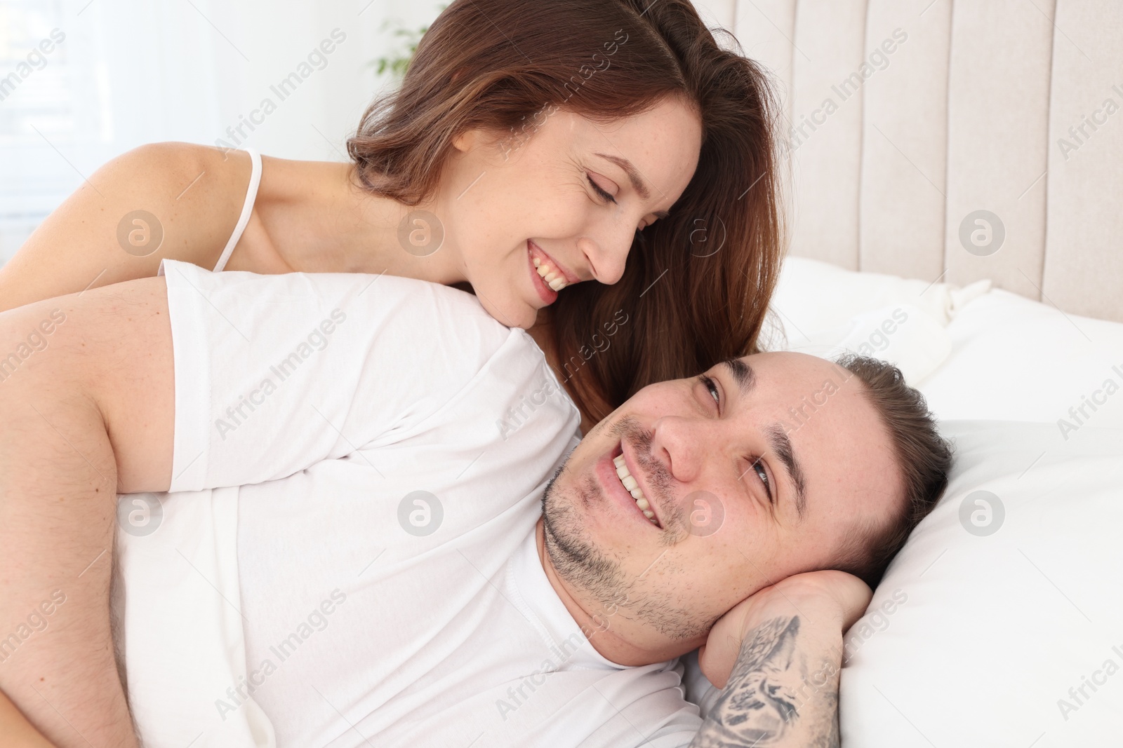 Photo of Happy couple spending time together on bed at home