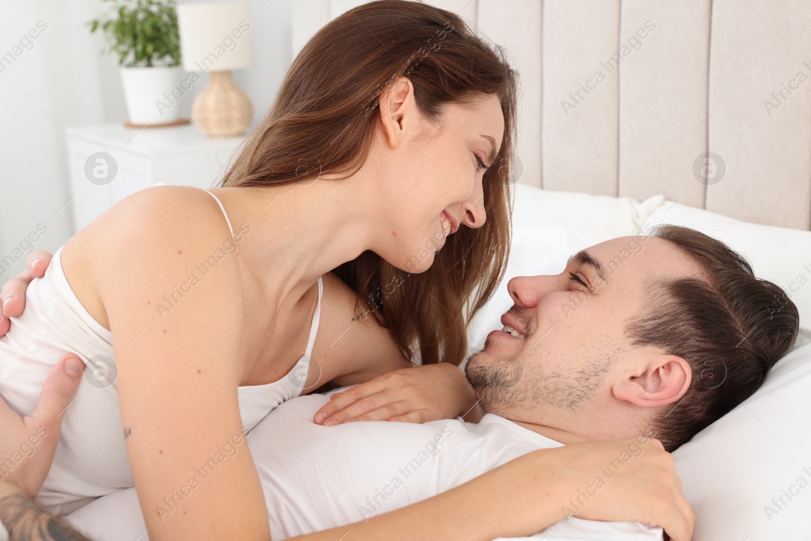 Photo of Happy couple spending time together on bed at home