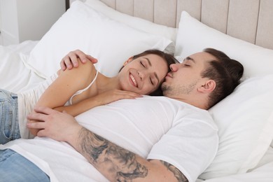 Photo of Happy couple lying on bed at home