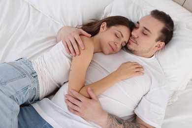 Cute couple napping in bed at home, top view