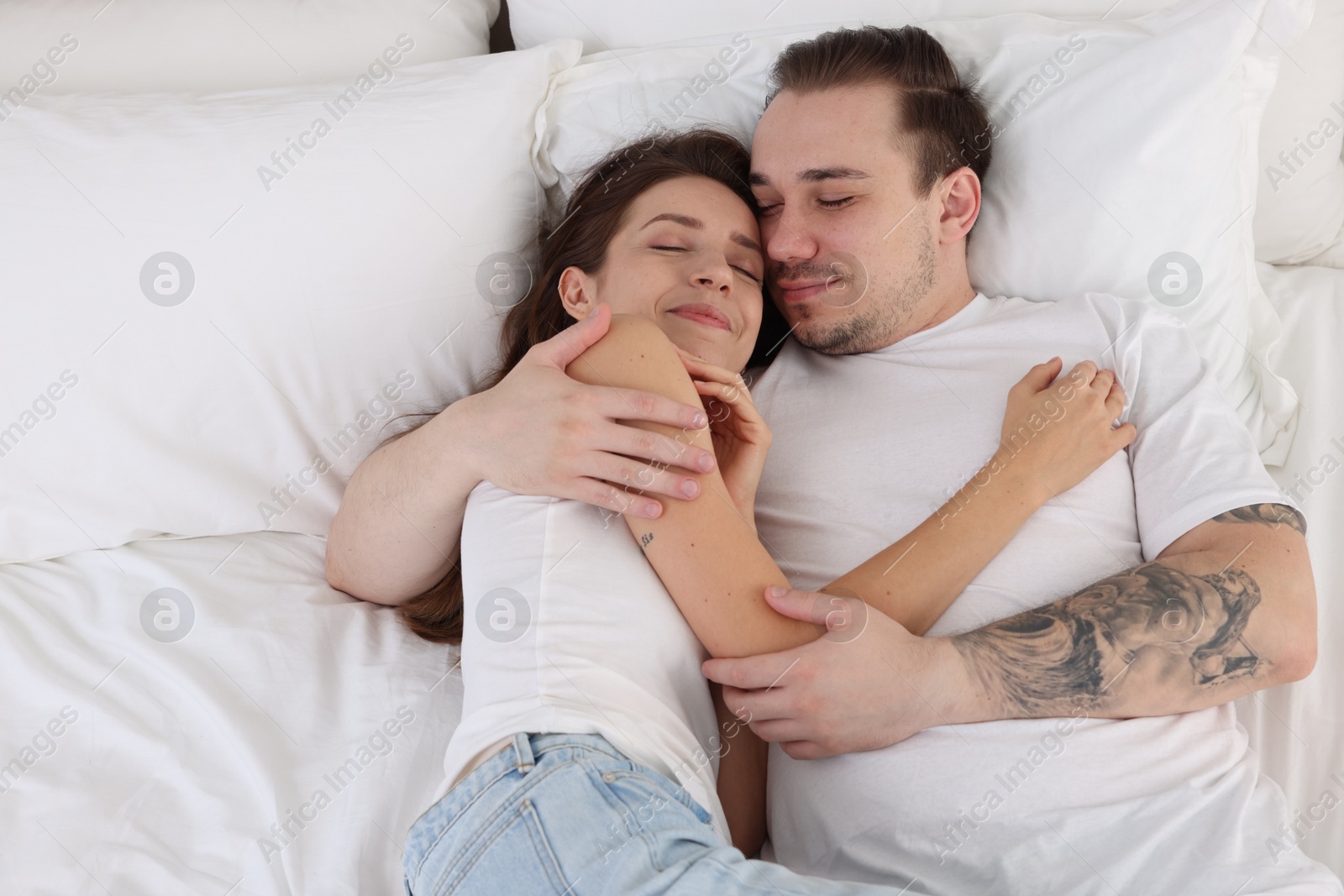 Photo of Cute couple napping on bed at home, top view