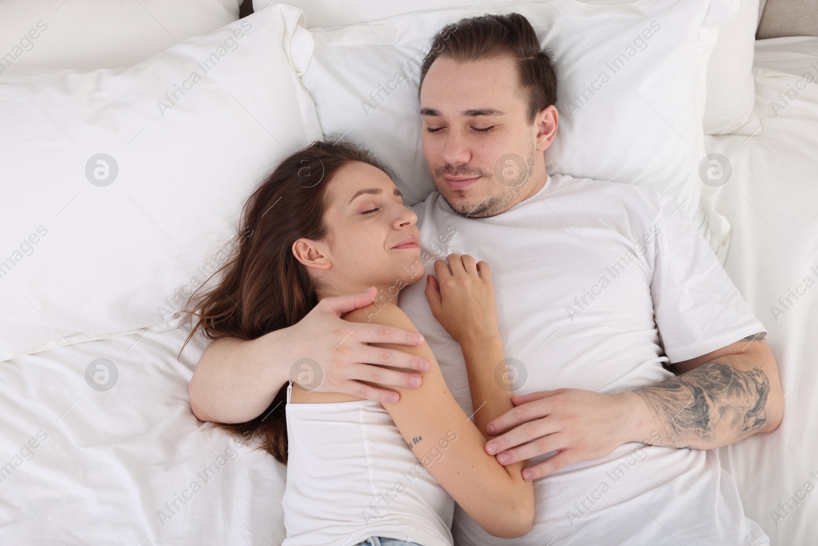 Photo of Cute couple napping on bed at home, top view