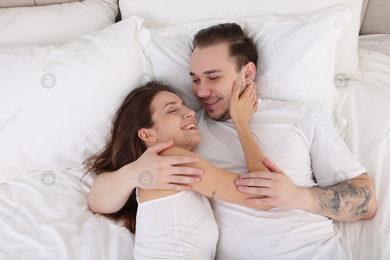 Photo of Happy couple spending time together on bed at home, top view