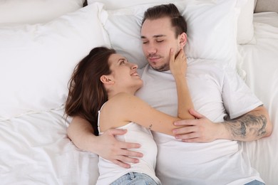 Photo of Happy couple spending time together on bed at home, top view