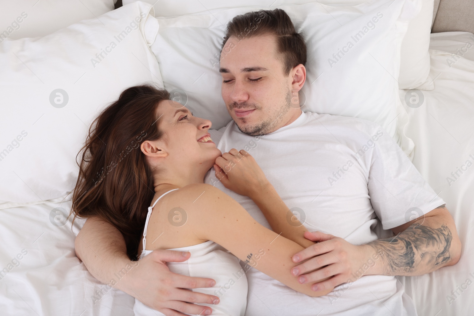 Photo of Happy couple spending time together on bed at home, top view