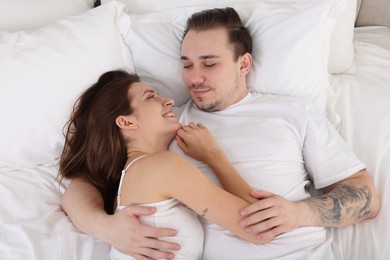 Happy couple spending time together on bed at home, top view