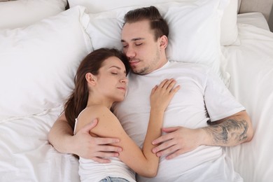 Photo of Cute couple napping on bed at home, top view