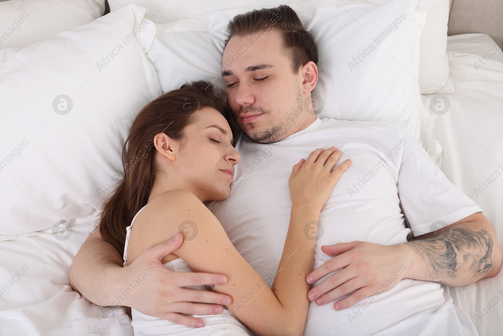 Photo of Cute couple napping on bed at home, top view