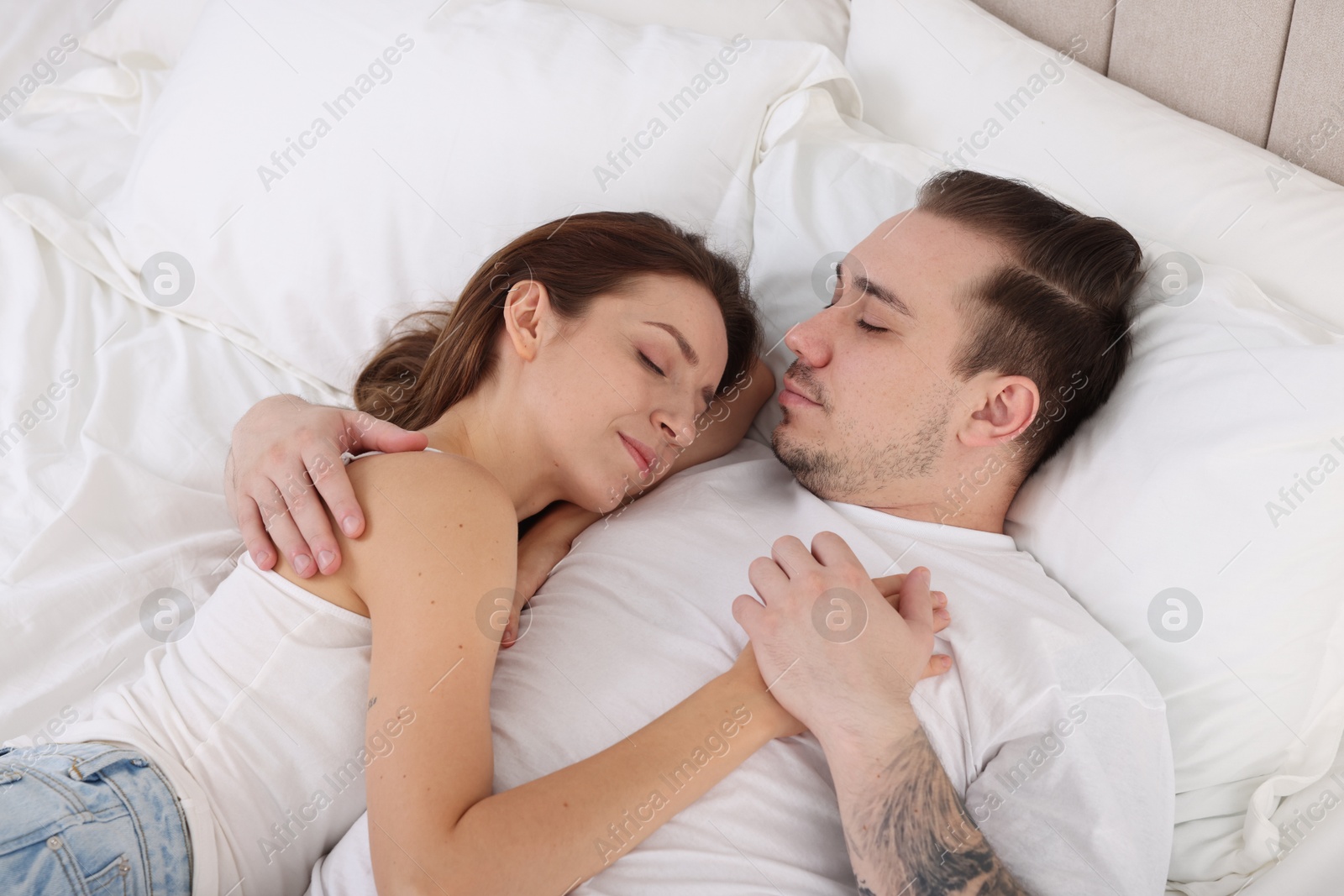 Photo of Cute couple napping on bed at home, top view