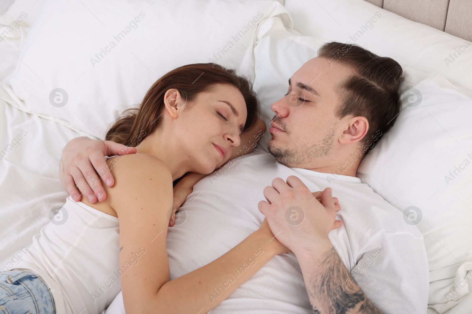 Photo of Cute couple napping on bed at home, top view