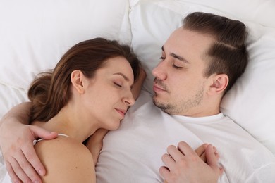 Cute couple napping on bed at home, top view