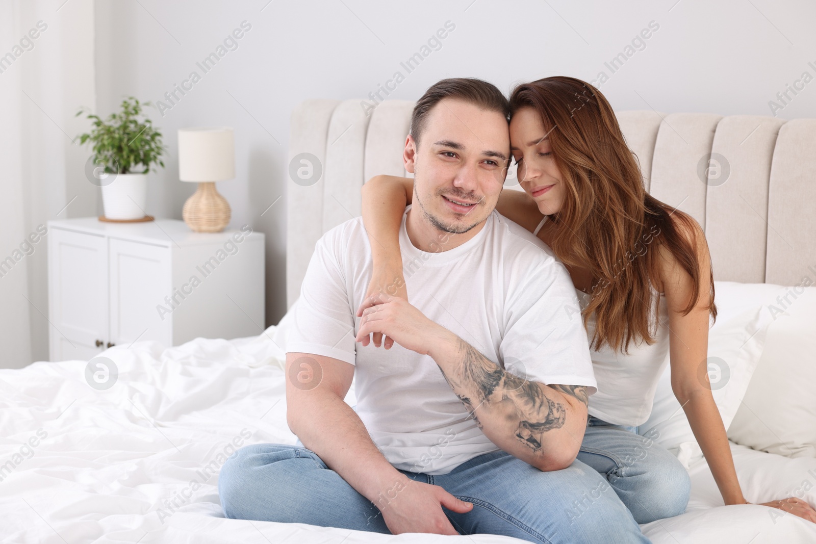 Photo of Cute couple spending time together on bed at home. Space for text