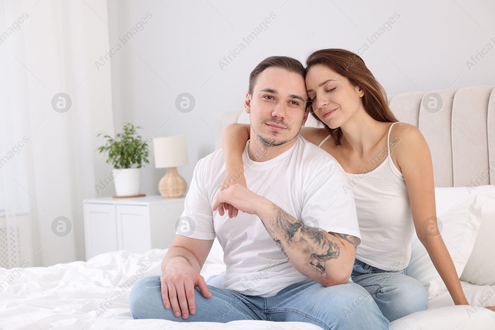 Photo of Cute couple spending time together on bed at home. Space for text