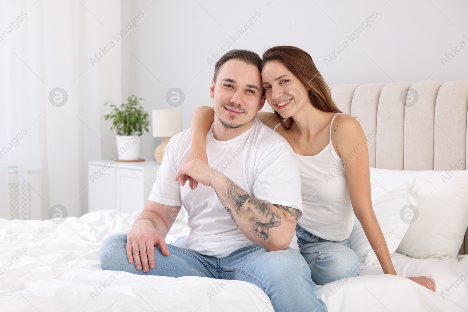 Photo of Happy couple spending time together on bed at home. Space for text