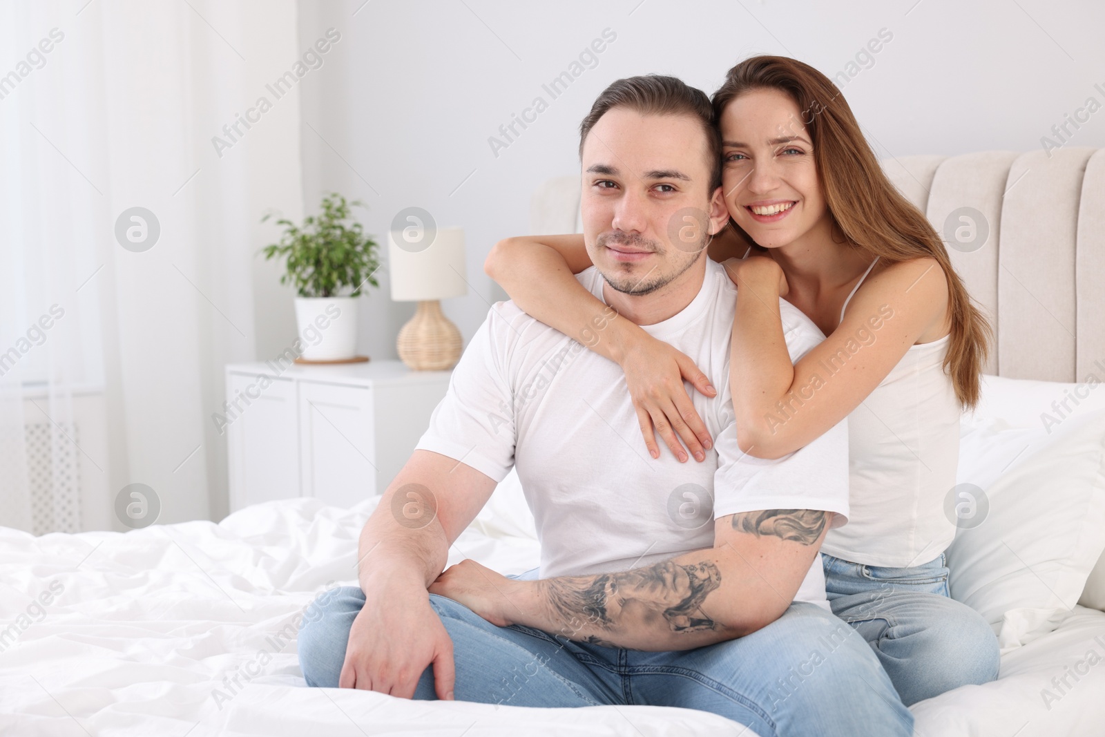 Photo of Happy couple spending time together on bed at home. Space for text