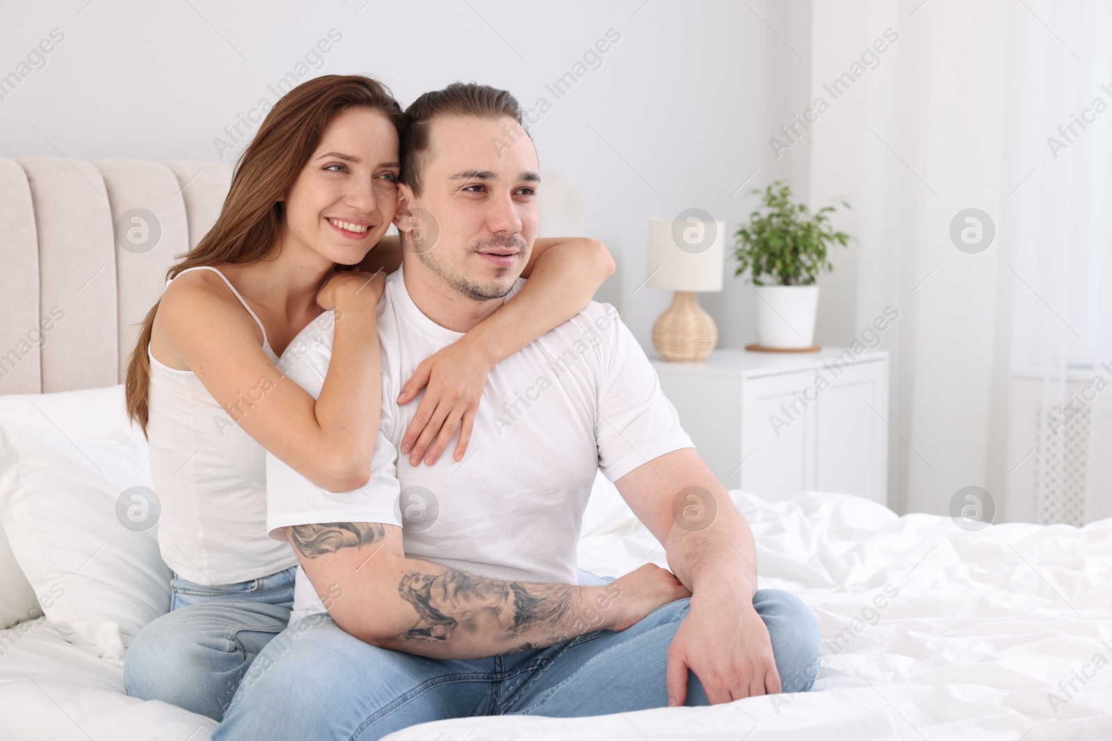 Photo of Happy couple spending time together on bed at home. Space for text