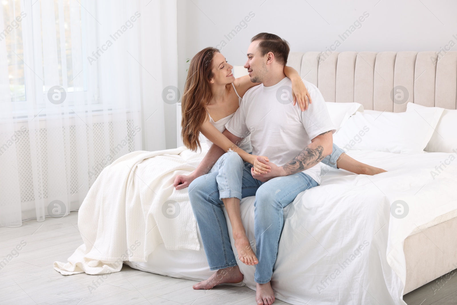 Photo of Happy couple spending time together on bed at home