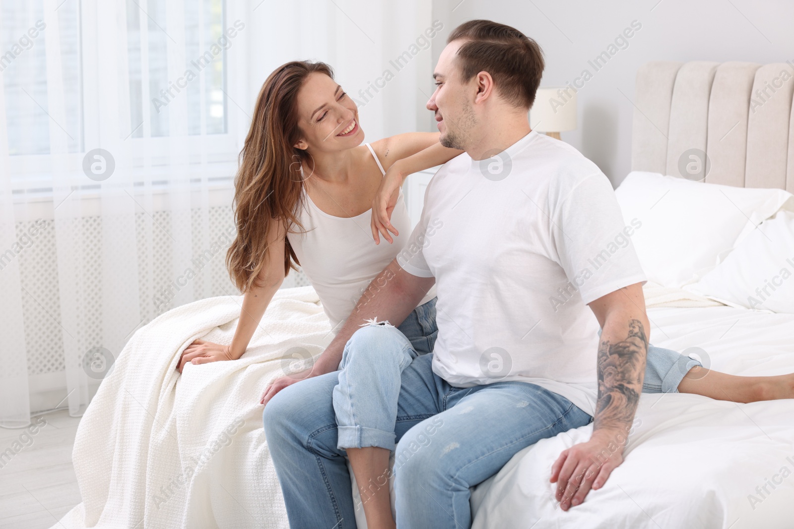 Photo of Happy couple spending time together on bed at home