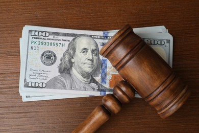 Photo of Alimony. Judge's gavel and stack of money on wooden table, top view