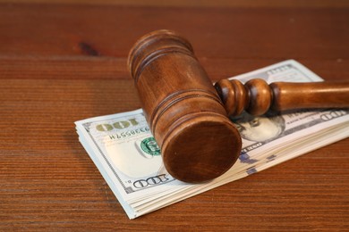 Photo of Alimony. Judge's gavel and stack of money on wooden table, closeup