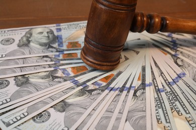 Photo of Alimony. Judge's gavel and pile of money on wooden table, closeup