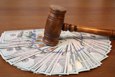 Photo of Alimony. Judge's gavel and pile of money on wooden table, closeup